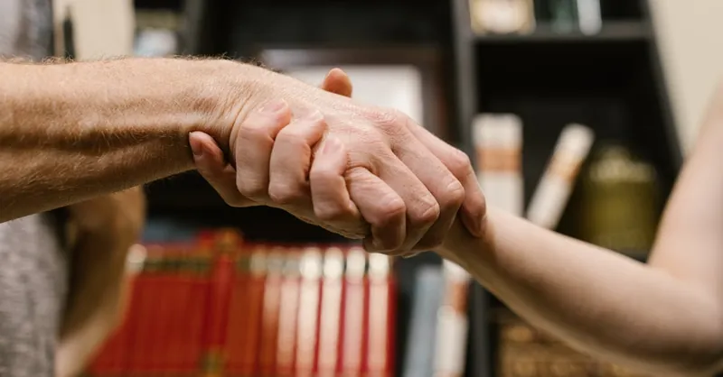 A close-up handshake symbolizing agreement, friendship, and trust inside a library.