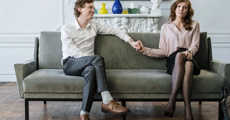 A couple in a therapy session holding hands, conveying support and connection.