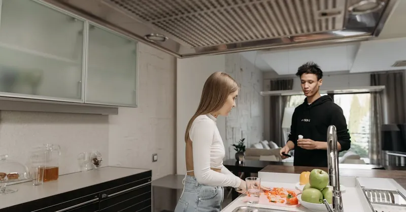 A couple in a modern kitchen engaged in food preparation, showcasing a cozy at-home atmosphere.