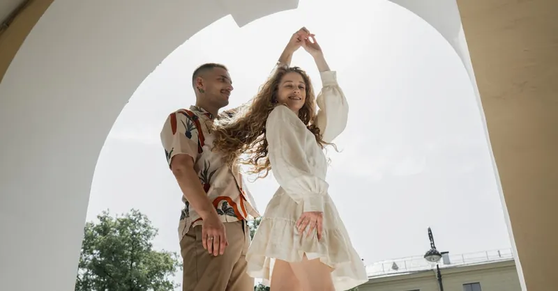 A couple joyfully dances under an outdoor arch, embodying togetherness and happiness.