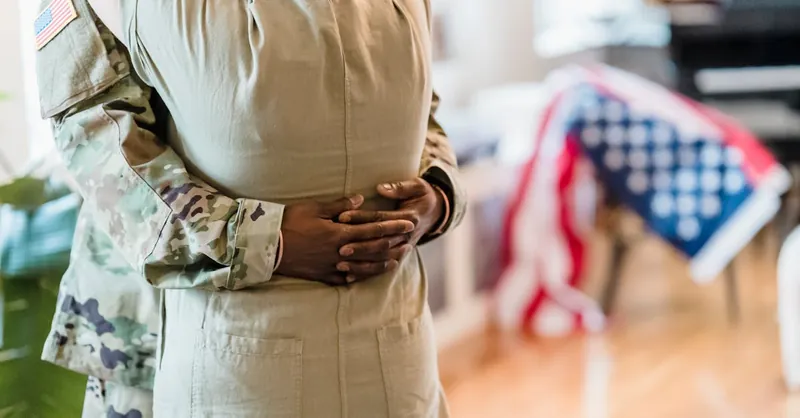 A heartfelt moment as a military couple embraces indoors, symbolizing unity and love.