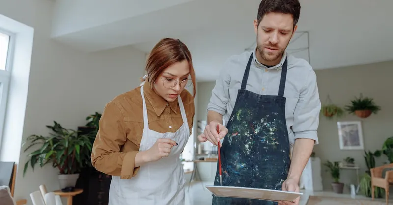 A man and woman engaged in painting as a hobby in a bright, indoor studio setting.