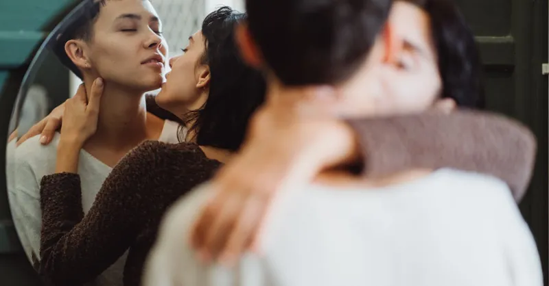 A couple shares an intimate embrace in front of a mirror, showing affection and love.