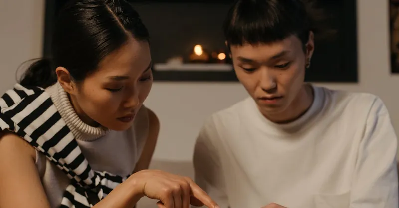 East Asian couple engaged in a thoughtful conversation indoors, hand gestures indicating focus.
