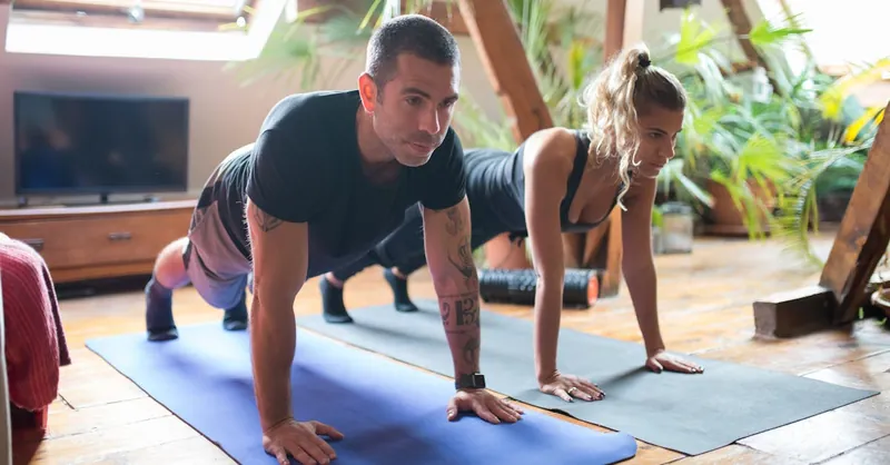 Man and woman doing yoga together at home, emphasizing fitness and healthy lifestyle.
