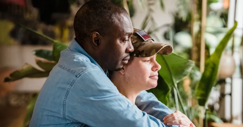 A soldier and partner share a loving embrace indoors, symbolizing reunion and love.