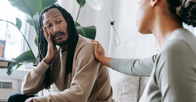 Two diverse individuals having an empathetic conversation in a cozy indoor setting.