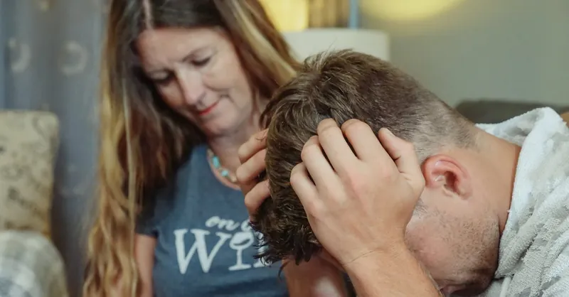 A mother provides emotional support to her stressed son indoors, conveying empathy and caring.