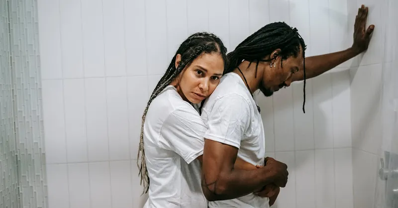 A thoughtful couple in an emotional embrace indoors, conveying support and love.