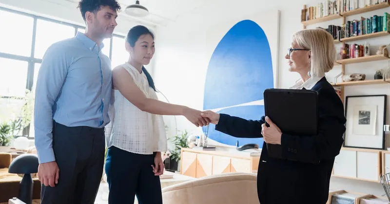 A therapist shakes hands with a couple after a successful therapy session.