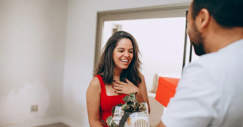 A happy woman receiving a gift from a man, capturing a moment of joy and affection.