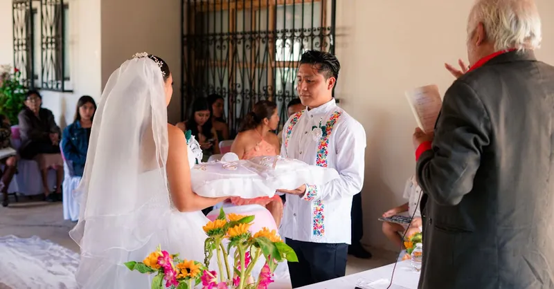 Traditional wedding ceremony featuring a bride and groom with cultural attire, surrounded by guests.