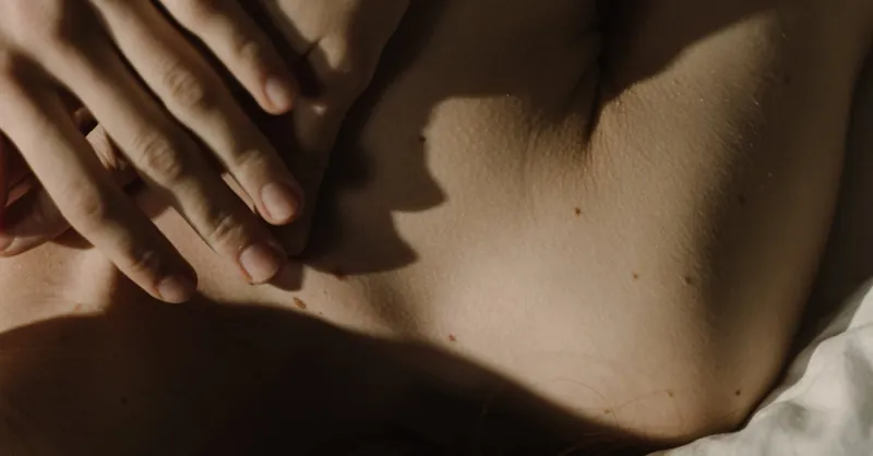 A gentle hand resting on skin with soft natural light creates a peaceful and intimate mood.
